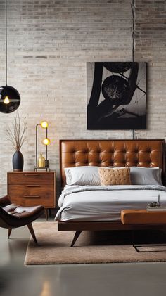 a bedroom with a bed, nightstands and chair in front of a brick wall