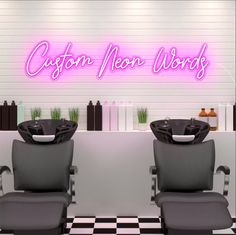 two gray chairs sitting next to each other in front of a sign that says custom neon words