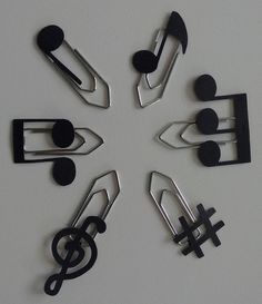 eight pieces of metal music notes arranged in the shape of a snowflake on a white surface