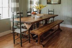 a wooden table with four chairs and a bench in front of it on a hard wood floor