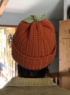 a man wearing an orange knitted hat with a green bow