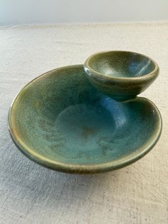 two bowls sitting on top of each other on a white tablecloth covered surface, one is green and the other is blue