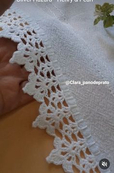 crocheted lace is being worked on by someone using scissors to sew it