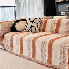 a living room with a striped couch and pillows on top of it, next to a window