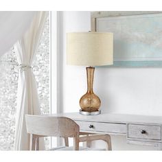 a white desk with a lamp on top of it next to a chair and table