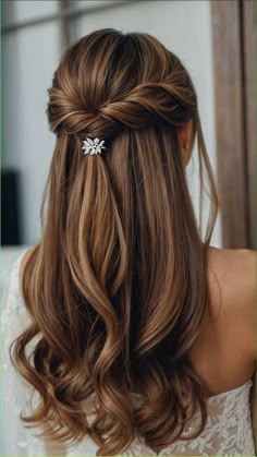 a woman with long brown hair wearing a half up braid and a flower clip in her hair