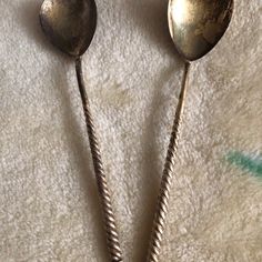 two silver spoons sitting on top of a white blanket