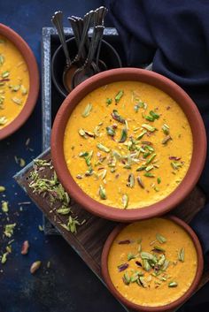 three bowls filled with soup sitting on top of a table