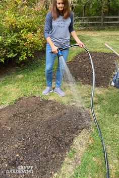 a woman watering her garden with a hose