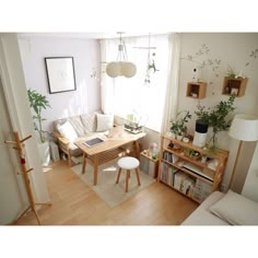 a living room filled with furniture next to a window covered in plants and bookshelves