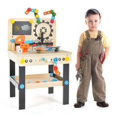 a young boy standing in front of a toy workbench with tools on it