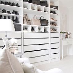 a living room filled with white furniture and lots of shelves full of purses on top of them