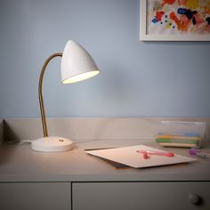 a desk lamp sitting on top of a table next to a notebook and pencils