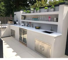 an outdoor kitchen with stainless steel appliances and plants growing on the wall above it,