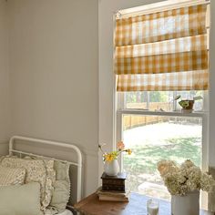 a bed sitting next to a window covered in yellow and white checkered bedspread