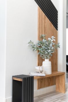 a plant is sitting on top of a wooden shelf next to a black and white vase