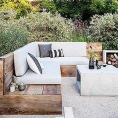 an outdoor living area with couches, tables and firewood stacked on top of each other