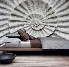 a bed sitting in front of a wall with a large shell on it's headboard