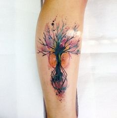 a woman's leg with a watercolor tree tattoo on her left arm and an arrow in the center