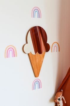 an ice cream cone with rainbows and clouds on the wall next to a toy horse