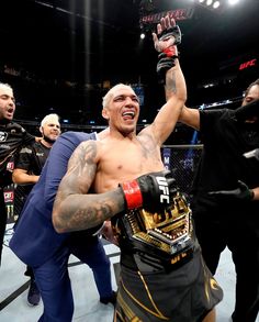 a man with his arm in the air holding up a boxing glove while standing next to other men