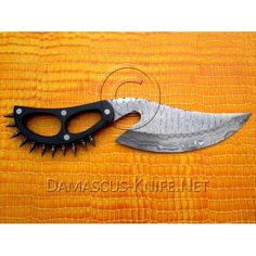 a knife that is laying on top of an orange cloth with black handles and spikes