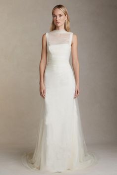 a woman in a white wedding dress with sheer neckline and tulle overlay