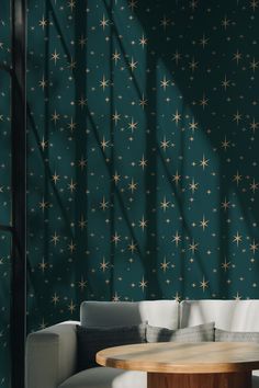 a living room with green walls and stars on the wall behind the couch, along with a round wooden table