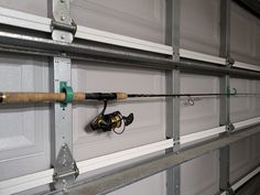 there is a fishing rod attached to the side of a garage door with two reels on it