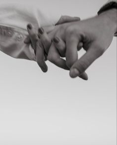 two people holding each other's hands in black and white