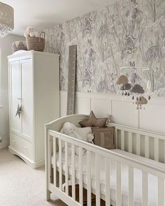 a baby's room with a crib, dresser and wallpapered walls