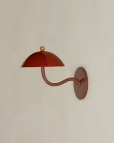 a red lamp mounted to the side of a white wall next to a brown light