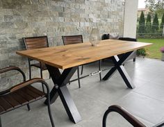 a wooden table sitting on top of a cement floor next to two chairs and a bench