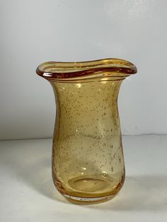 a yellow glass vase sitting on top of a white table