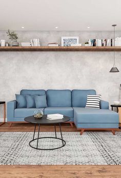 a living room with a blue couch, coffee table and bookshelf on the wall