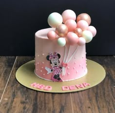 a minnie mouse cake with pink and white balloons