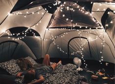 a person laying in a tent with lights on the ceiling