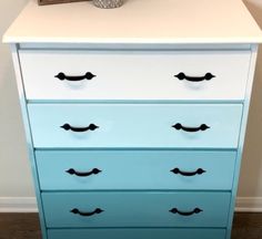 a blue and white dresser with black handles on it's drawers in a room