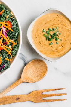 two bowls filled with different types of food next to wooden spoons on a marble surface