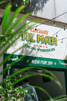 the sign for an al mar mexican restaurant in new york, usa is seen through some green leaves