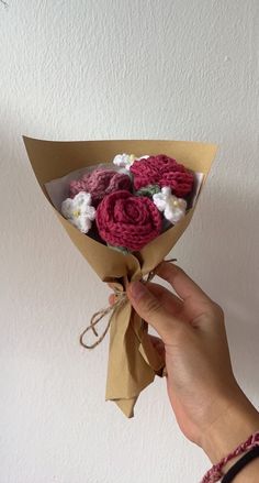 a person is holding a bouquet of flowers in their left hand and the other hand has a brown paper wrapped around it