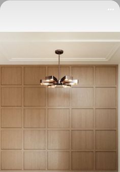 a chandelier hanging from the ceiling in a room with wood paneling on the walls