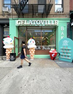 a man walking past a store front with balloons in the shape of ice cream cones