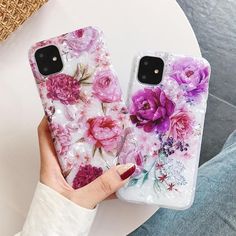 two cases with flowers painted on them are held up by someone's hand in front of a white table