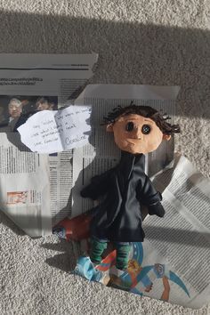 a stuffed doll is laying on the floor next to newspapers and papers that have been placed over it