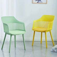 two colorful chairs sitting next to each other in front of a wall with a painting on it