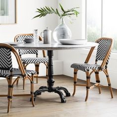 a dining room table with chairs and a vase on the table in front of it