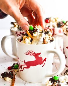 someone is dipping marshmallows into a mug filled with candy and candies