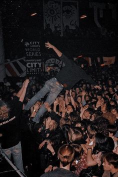 a crowd of people at a concert with their arms in the air and one person jumping up into the air