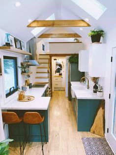 the interior of a tiny home with wood flooring and white walls, along with wooden stairs